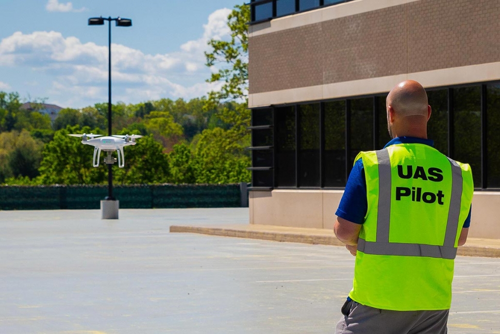 Jeffrey Gordon, owner of Ideal Video Strategies, operating a video recording drone in parking lot - rear view